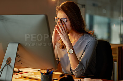 Buy stock photo Shot of an attractive young businesswoman looking stressed while working late in the office