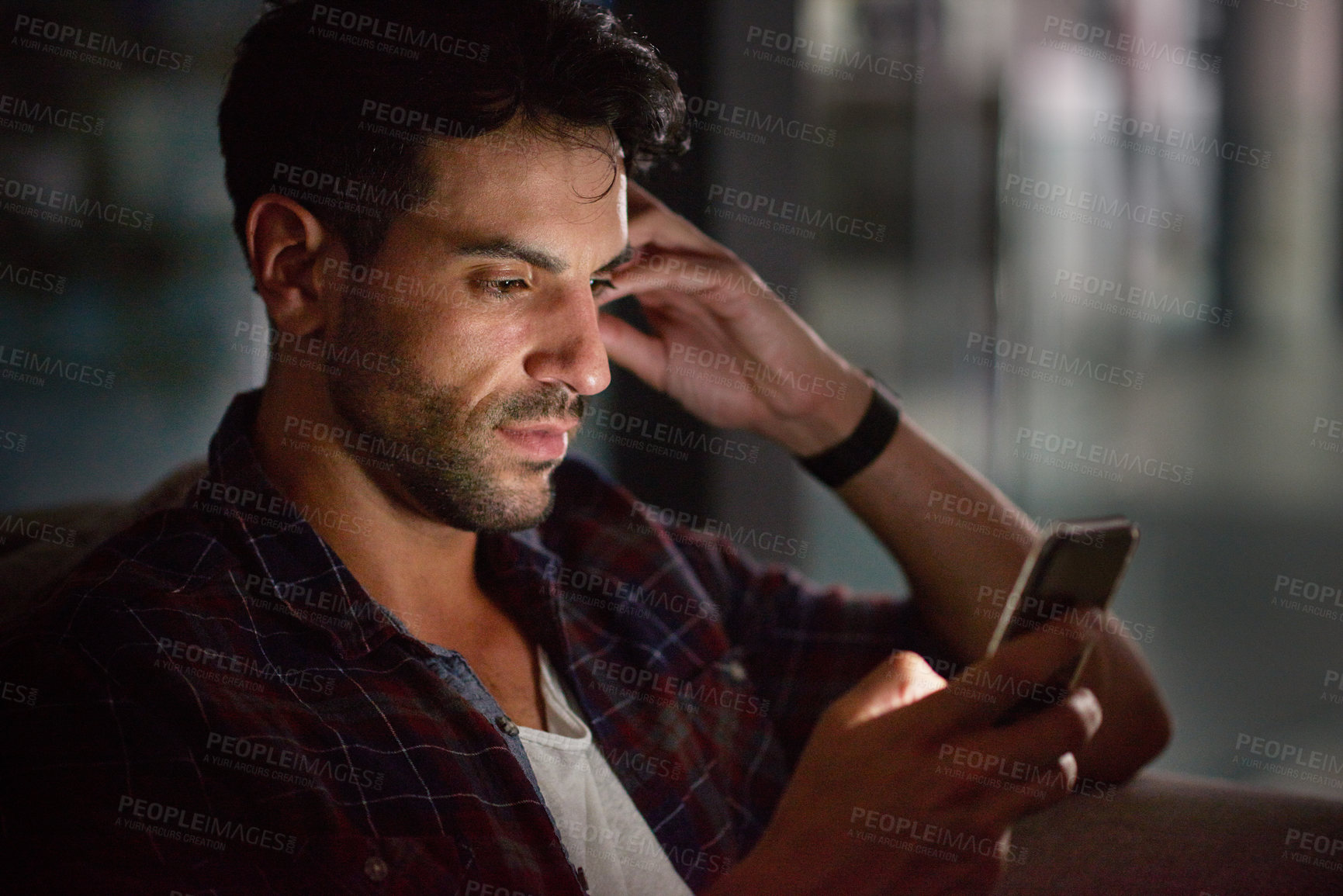 Buy stock photo Man, phone and night in office at startup with reading, texting and communication on web in overtime. Person, smartphone and thinking for notification, networking and scroll on app at creative agency