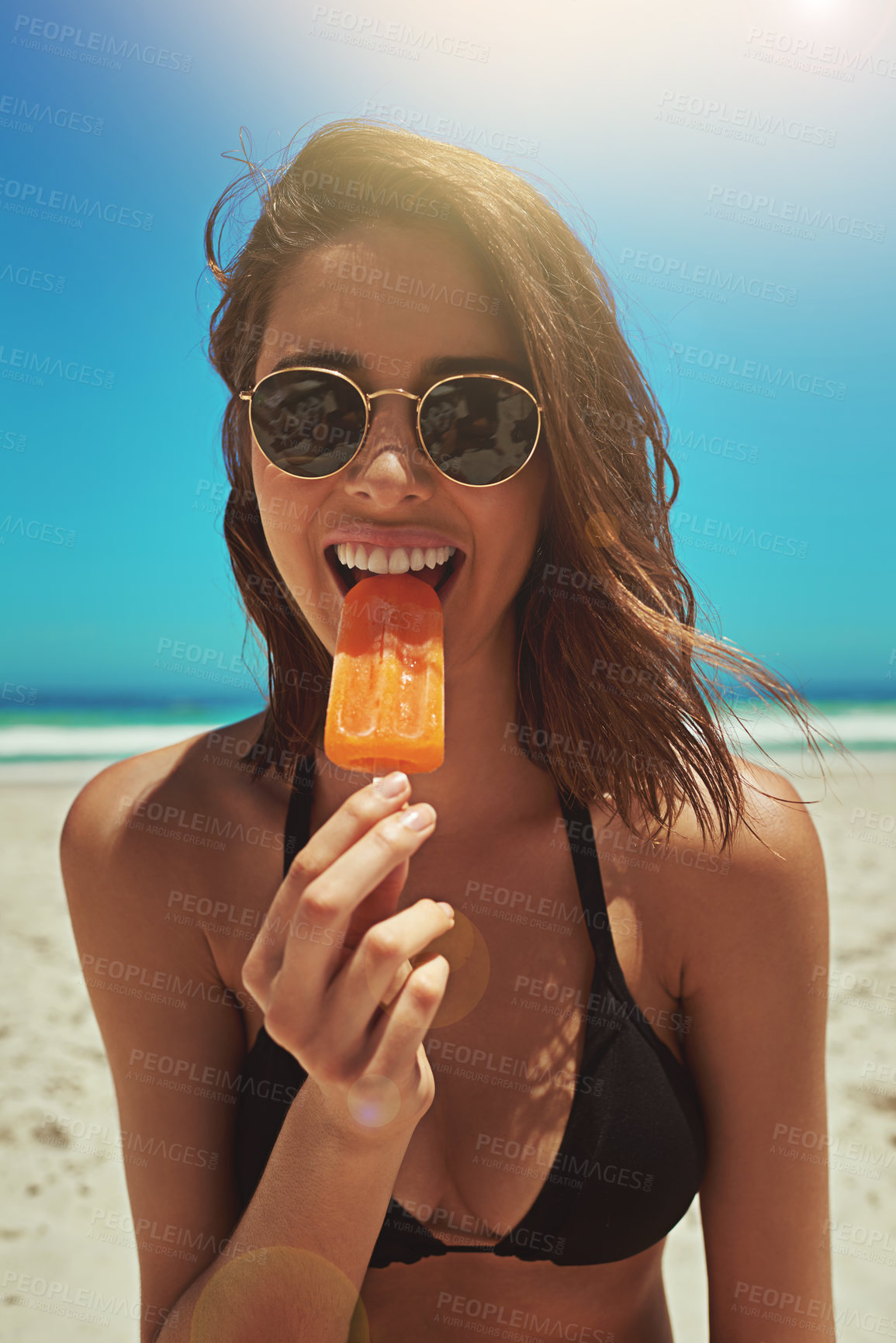 Buy stock photo Portrait of a sexy young woman enjoying an ice lolly at the beach