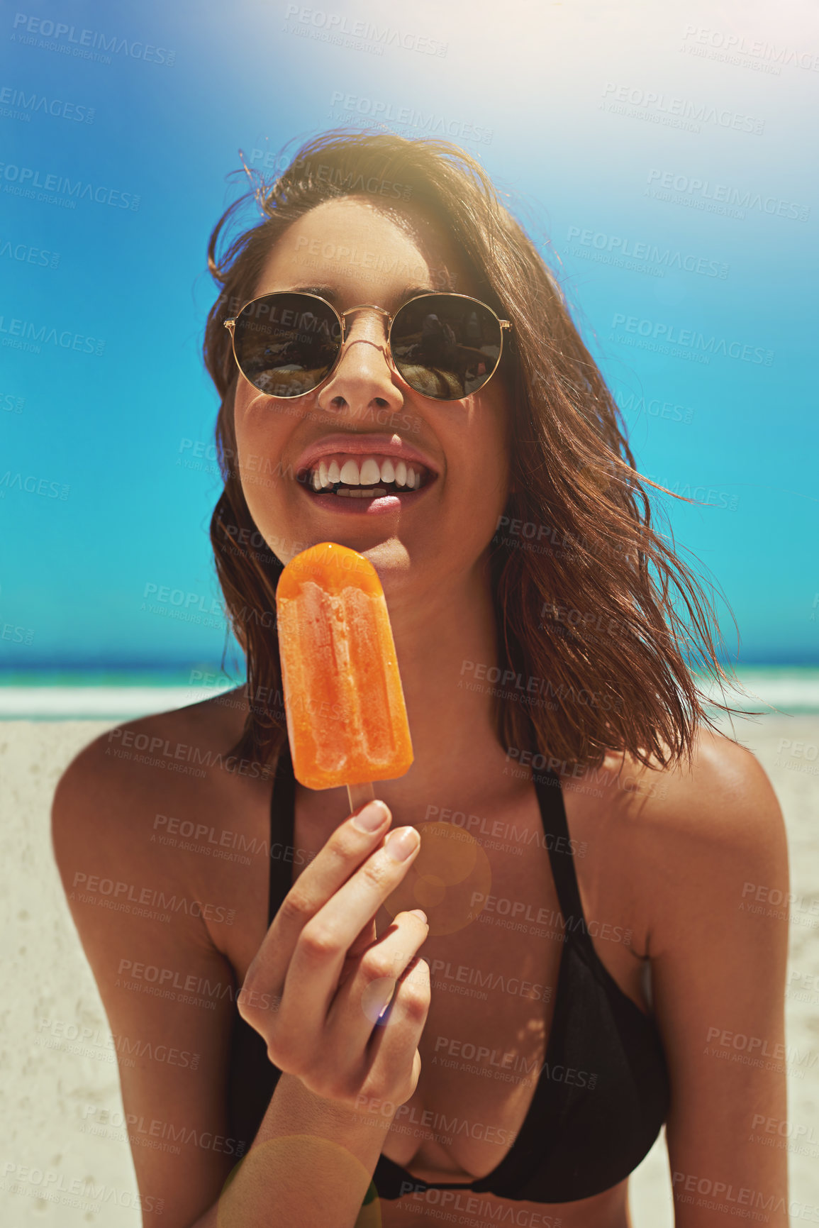 Buy stock photo Portrait of a sexy young woman enjoying an ice lolly at the beach