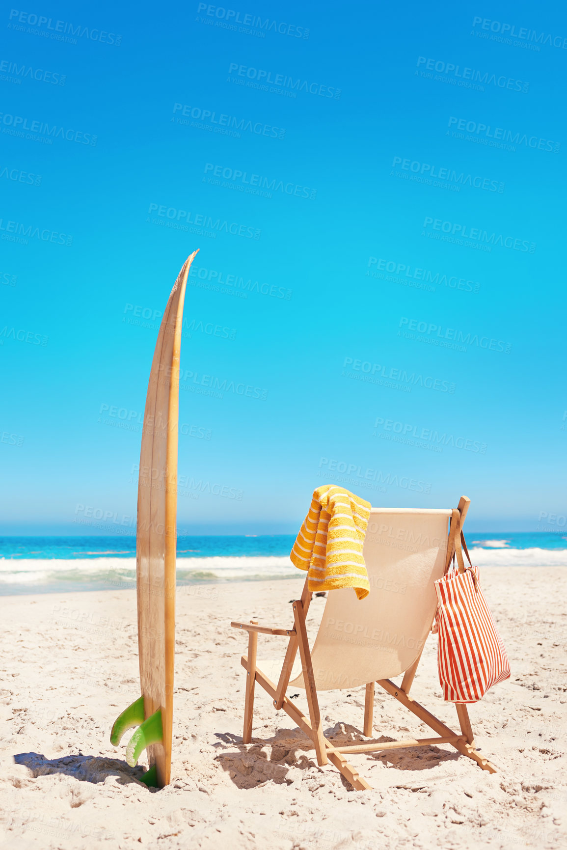 Buy stock photo Shot of a lounge chair and a surfboard on the beach