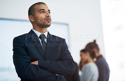 Buy stock photo Shot of a young businessman in the office with his colleagues in the background