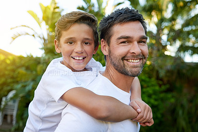 Buy stock photo Portrait of a father carrying his son on his back outside