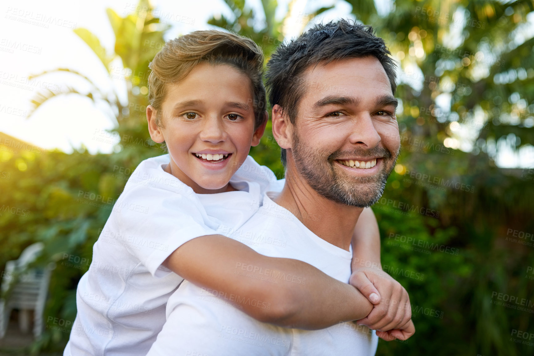 Buy stock photo Portrait of a father carrying his son on his back outside