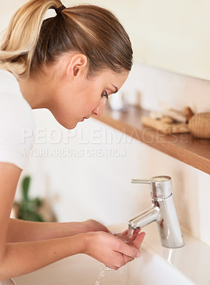 Buy stock photo Cropped shot of a young woman washing her face in the bathroom