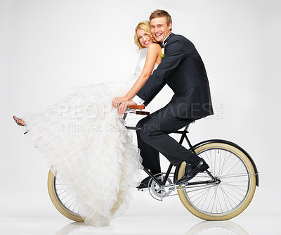 Buy stock photo Studio shot of a newlywed couple riding an old bicycle