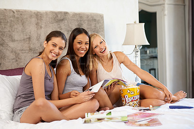 Buy stock photo Happy friends, portrait and girls reading magazine in bedroom, food and eating popcorn snack together at party. Smile, women and group with journal in home, funny and laugh in bed to relax in house