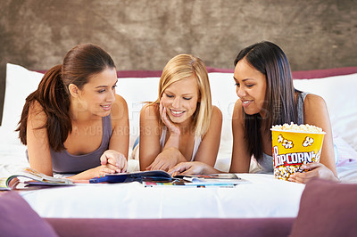 Buy stock photo Smile, friends and women reading magazine in bedroom, food and eating popcorn snack together at party. Happy, girls and group with journal in home for conversation or bonding in bed to relax in house