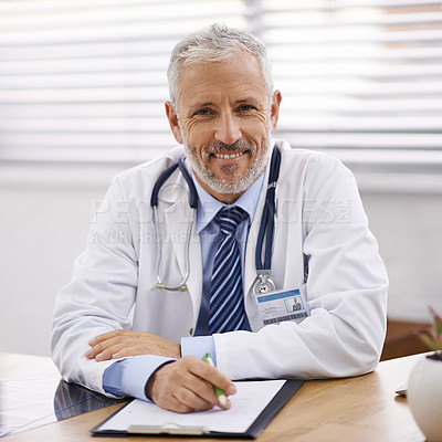 Buy stock photo Portrait of a mature male doctor sitting at his desk