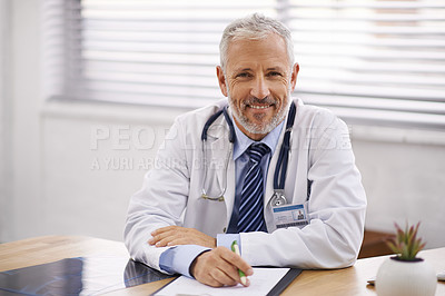 Buy stock photo Portrait of a mature male doctor sitting at his desk