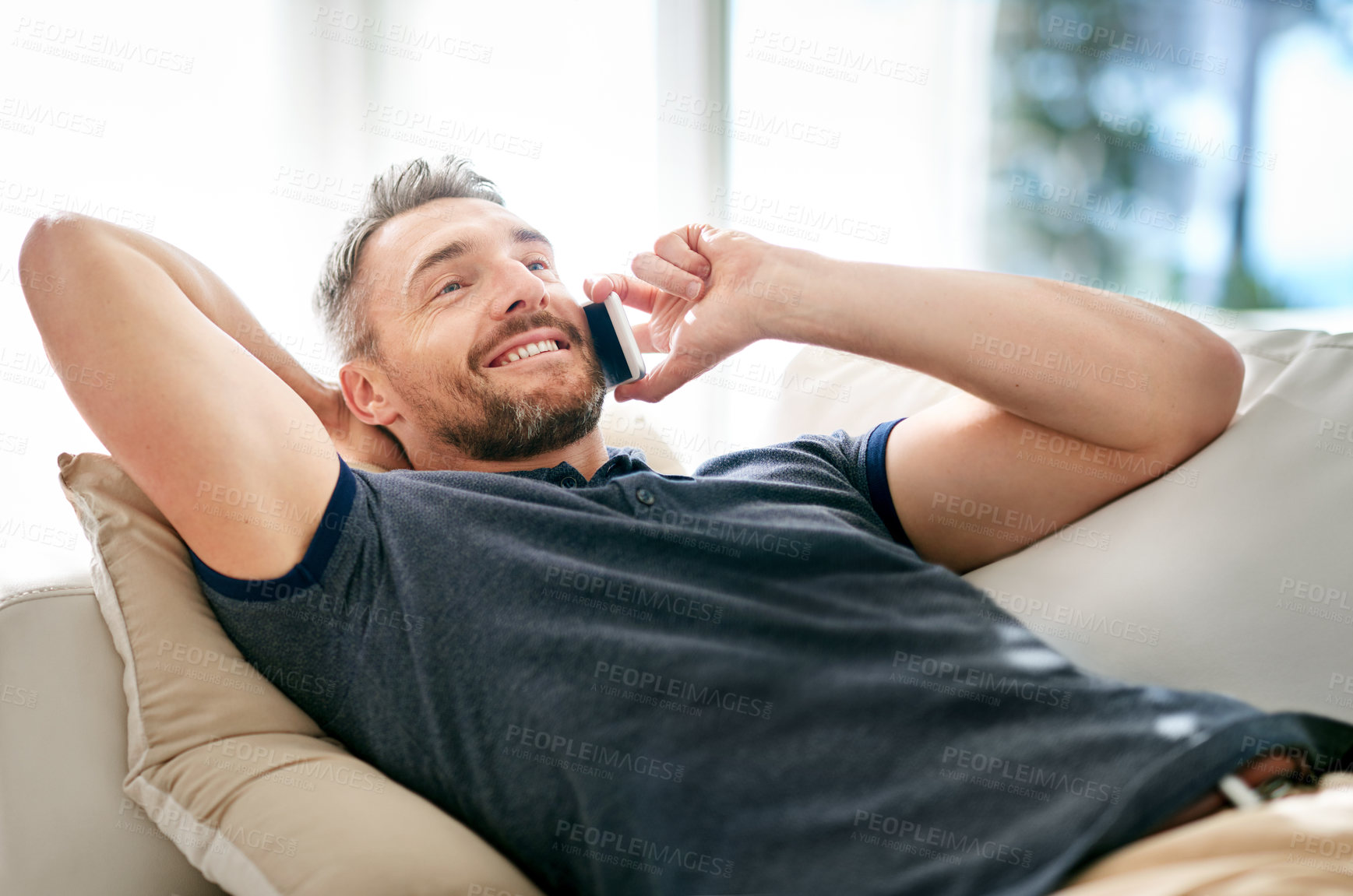 Buy stock photo Happy guy, phonecall and smile for audio conversation, funny joke and good news on sofa in lounge. Young person, cheerful and mobile phone for talk, chatting or speaking for discussion and relax