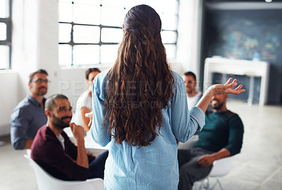 Buy stock photo Rearview shot of a woman giving a presentation to colleagues in an office