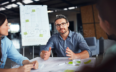 Buy stock photo Shot of a mature manager talking to his team while sitting around a table in an office