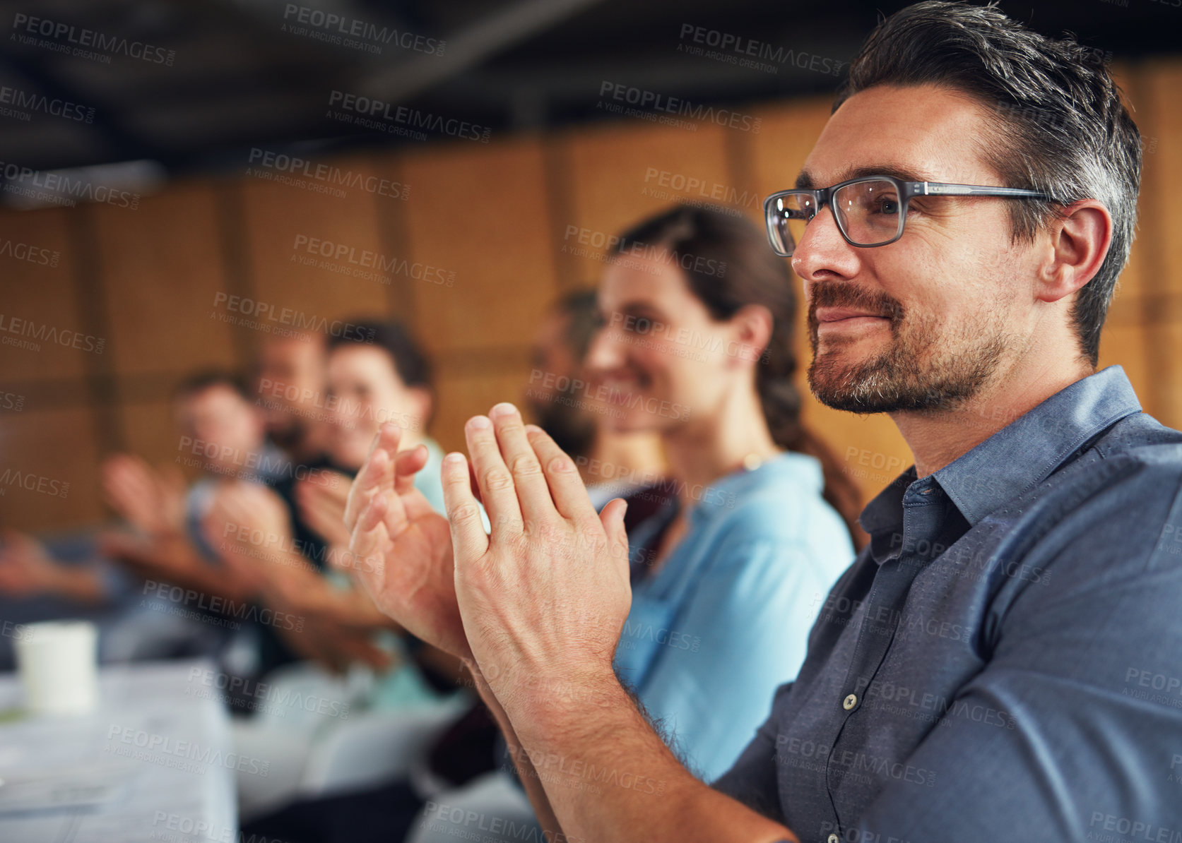 Buy stock photo Shot of a group of colleagues clapping together at a table in an office