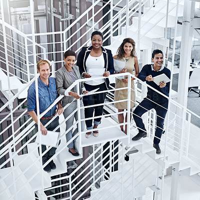 Buy stock photo Portrait of a group of smiling coworkers standing on stairs in a modern office