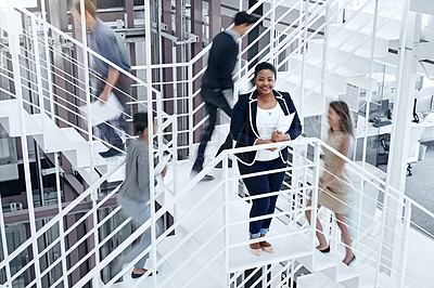 Buy stock photo Portrait of a young professional standing on a stairs with colleagues rushing around her