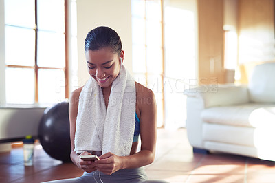 Buy stock photo Cropped shot of a young woman checking her playlist while exercising at home