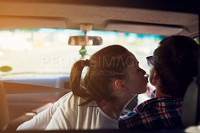 Buy stock photo Rearview shot of a young woman kissing her boyfriend while he drives a car