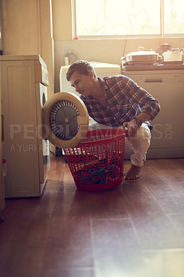 Buy stock photo Shot of a young man doing laundry at home