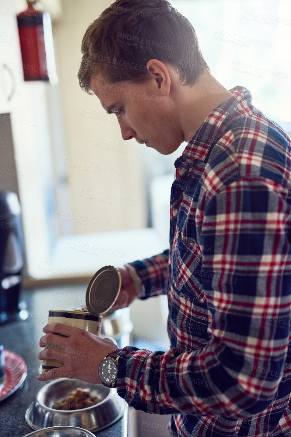 Buy stock photo Shot of a young man filling a bowl with pet food at home