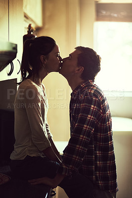 Buy stock photo Shot of an affectionate young couple sharing a romantic kiss in the kitchen