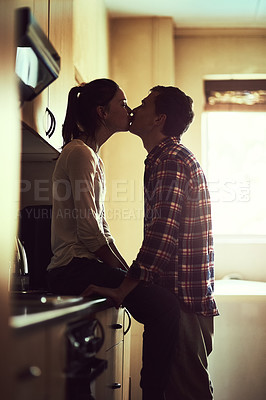 Buy stock photo Shot of an affectionate young couple sharing a romantic kiss in the kitchen
