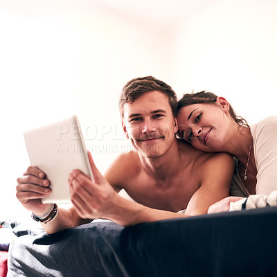 Buy stock photo Portrait of a young couple spending a lazy day in bed with their tablet