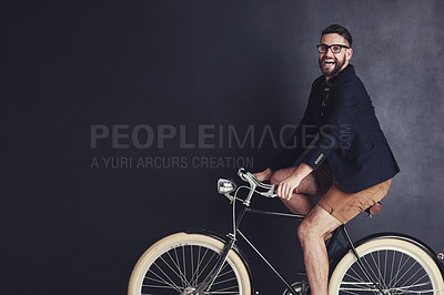 Buy stock photo Portrait of a trendy young man riding a bicycle in studio