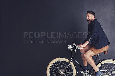 Buy stock photo Shot of a trendy young man riding a bicycle in studio