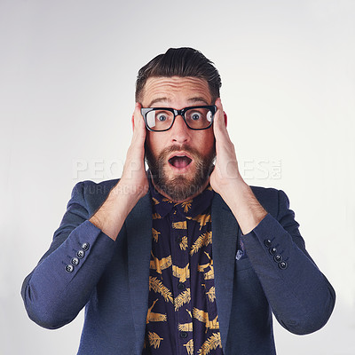 Buy stock photo Portrait of a surprised young man holding on to his glasses in studio