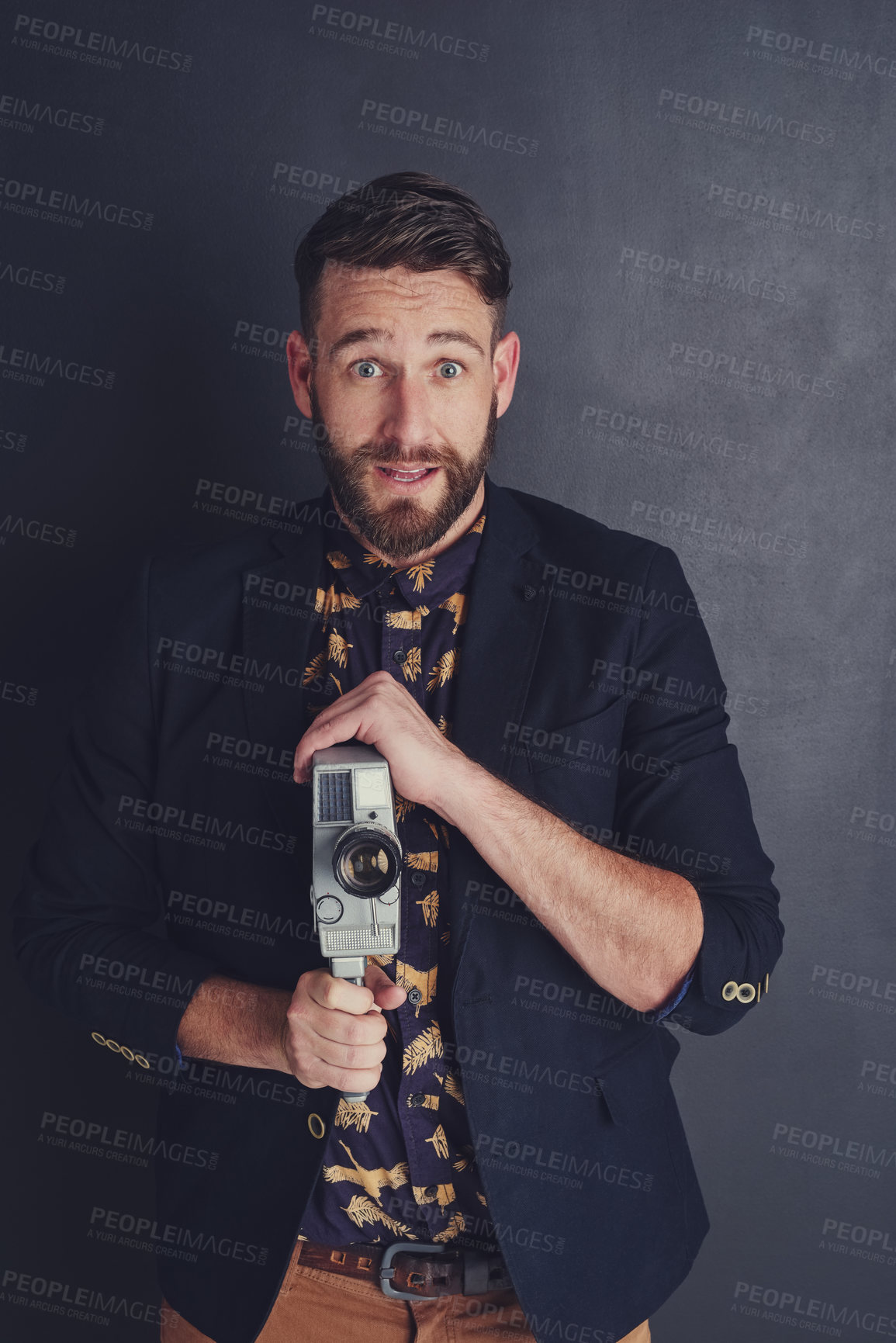 Buy stock photo Portrait of a trendy young man with a vintage camera posing against a dark background