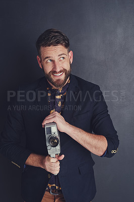 Buy stock photo Shot of a trendy young man with a vintage camera posing against a dark background