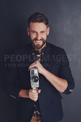 Buy stock photo Portrait of a trendy young man with a vintage camera posing against a dark background