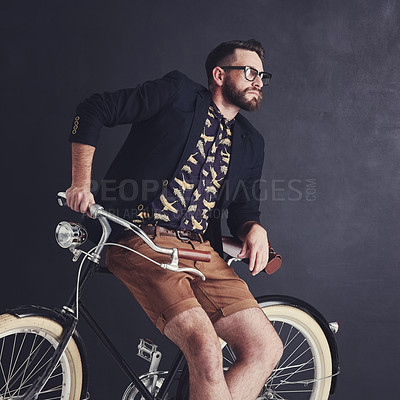 Buy stock photo Shot of a trendy young man posing in studio with his bicycle