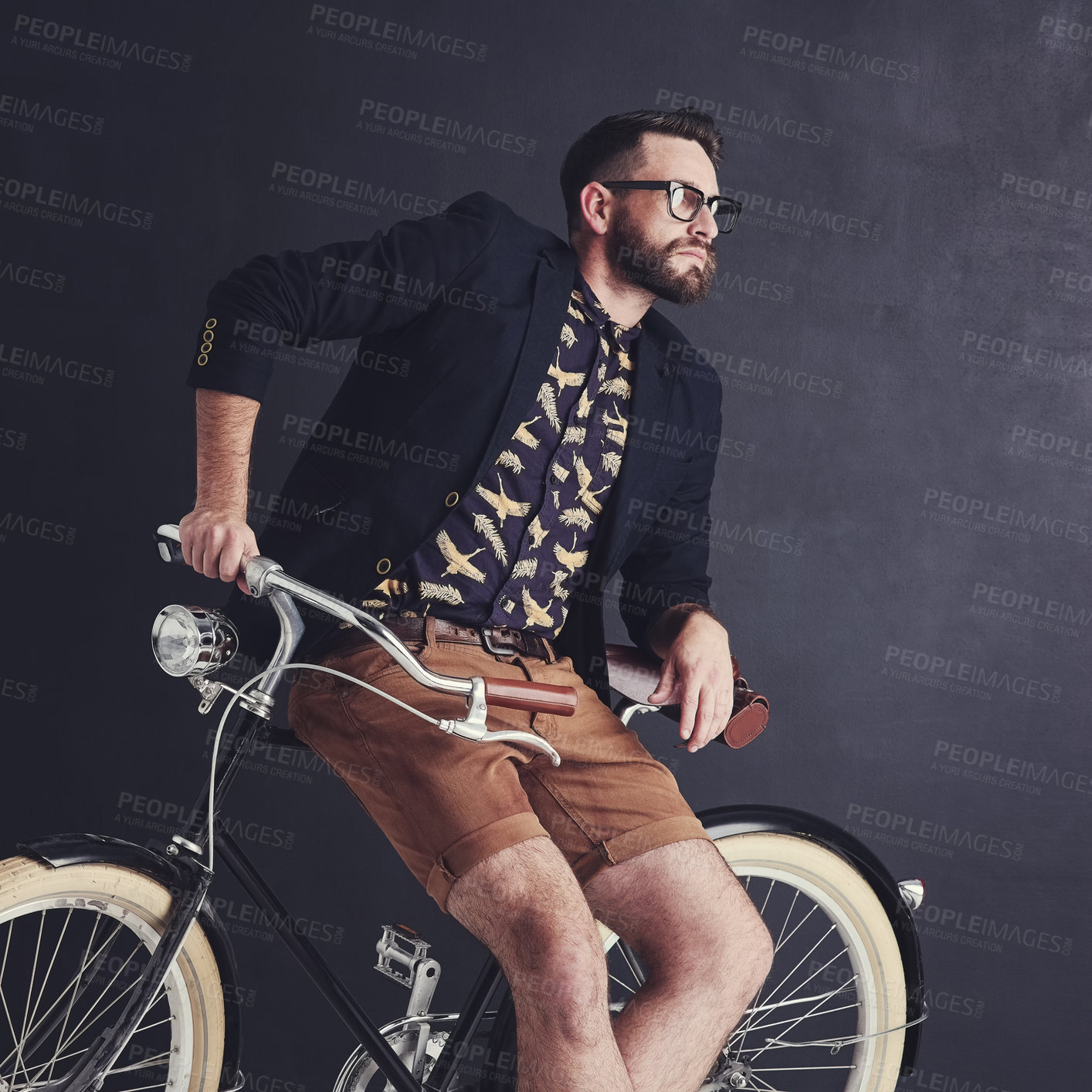 Buy stock photo Shot of a trendy young man posing in studio with his bicycle
