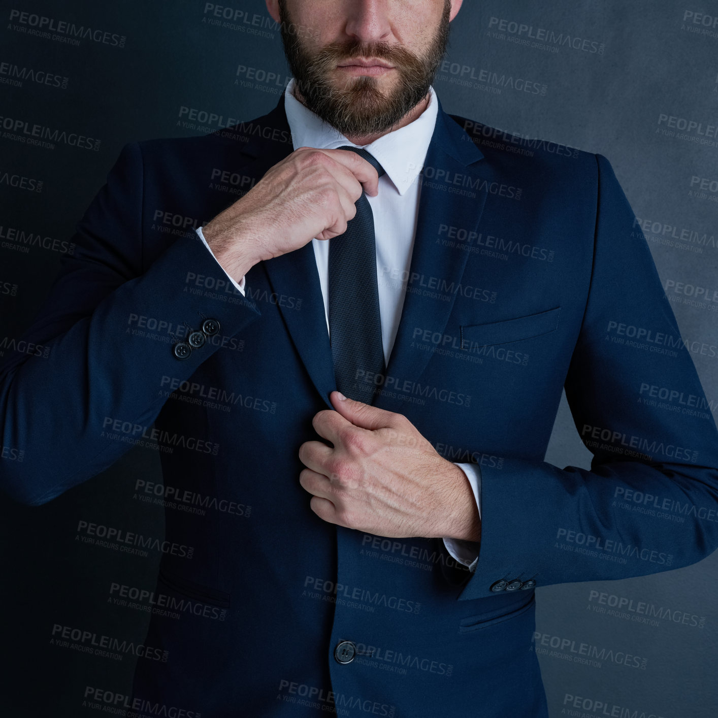 Buy stock photo Shot of an unidentifiable businessman adjusting his tie against a dark background