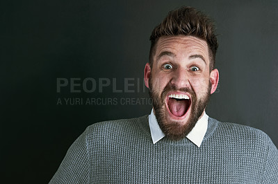 Buy stock photo Portrait of an ecstatic young man posing against a dark background in studio