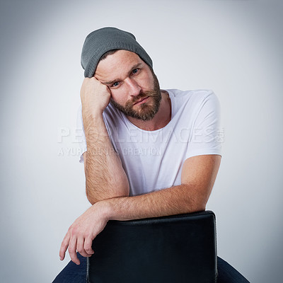 Buy stock photo Portrait of a moody young man posing on a chair in the studio