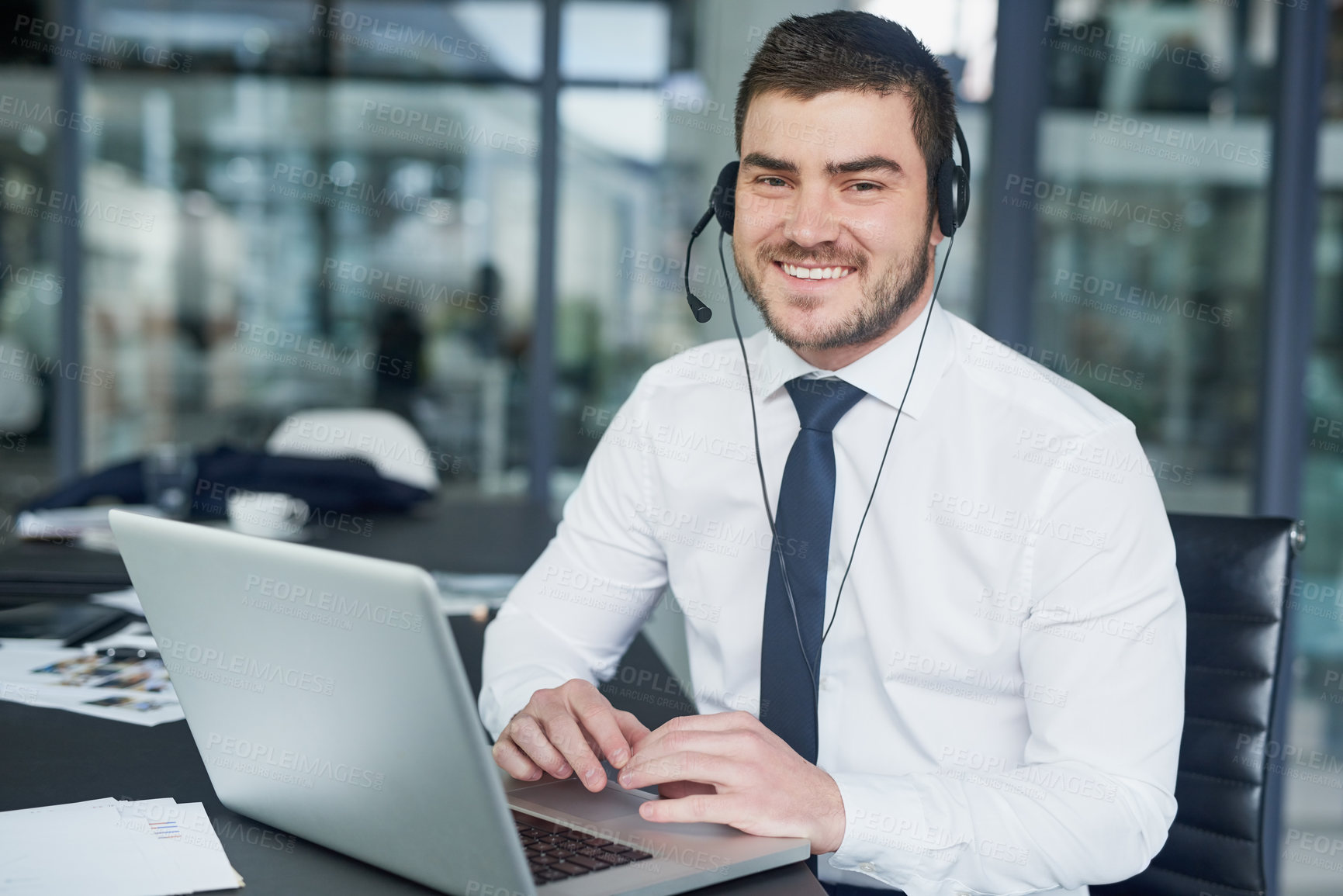 Buy stock photo Portrait of a young customer service representative wearing a headset while sitting at his workstation in an office