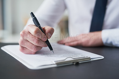 Buy stock photo Cropped shot of a businessman filling out paperwork on a clipboard while sitting at a table in an office