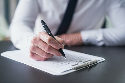 Buy stock photo Cropped shot of a businessman filling out paperwork on a clipboard while sitting at a table in an office