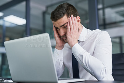 Buy stock photo Shot of a stressed out young businessman working on a laptop in an office