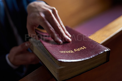 Buy stock photo Cropped shot of a man opening a bible while sitting in a pew at church