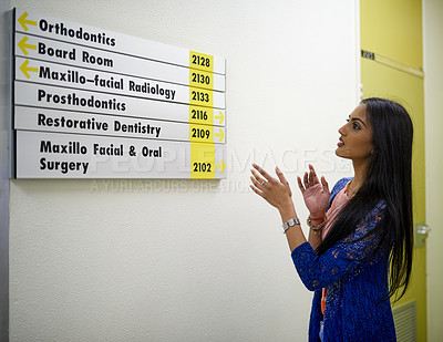 Buy stock photo Shot of an attractive young woman reading a directory on the wall of a medical center