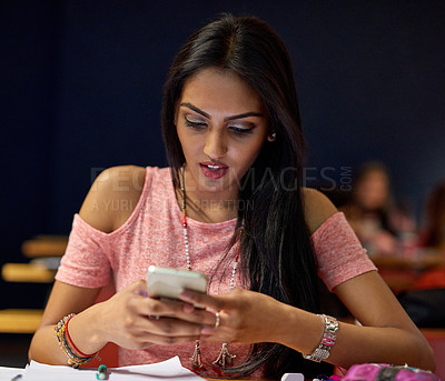 Buy stock photo Shot of a university student using her cellphone while sitting in a lecture hall