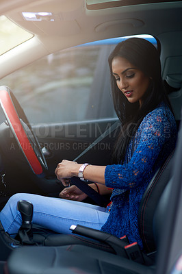 Buy stock photo Shot of an attractive young woman buckling up before driving her car