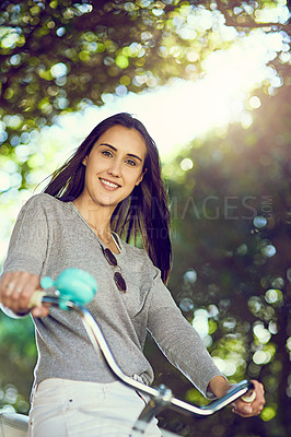 Buy stock photo Portrait of an attractive young woman riding her bicycle outside