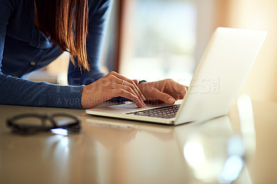 Buy stock photo Shot of an unidentifiable woman using her laptop while standing in her kitchen