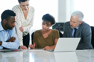 Buy stock photo Shot of a group of colleagues working together on a laptop while sitting at a desk in an office