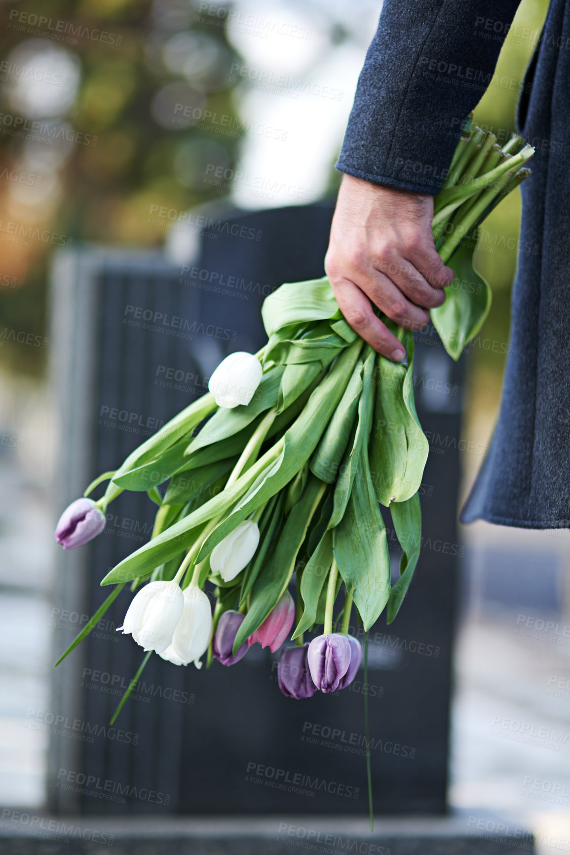 Buy stock photo Cropped shot of a man visiting a gravesite with a bunch of flowers